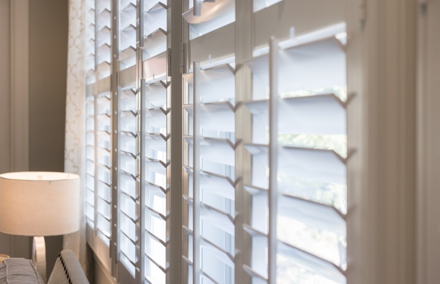 plantation shutters living room with tan walls and white shutters. ZBORRHV