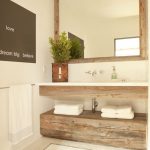 Lovely powder room features reclaimed wood mirror over floating