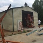 crew building a commercial metal garage, attaching the trim. TAEQWHY