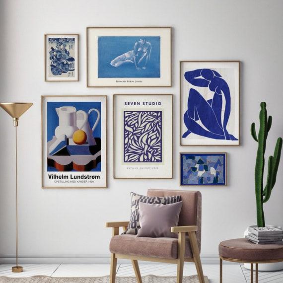 Create​ a gallery wall using blue-themed art in​ your living‌ room