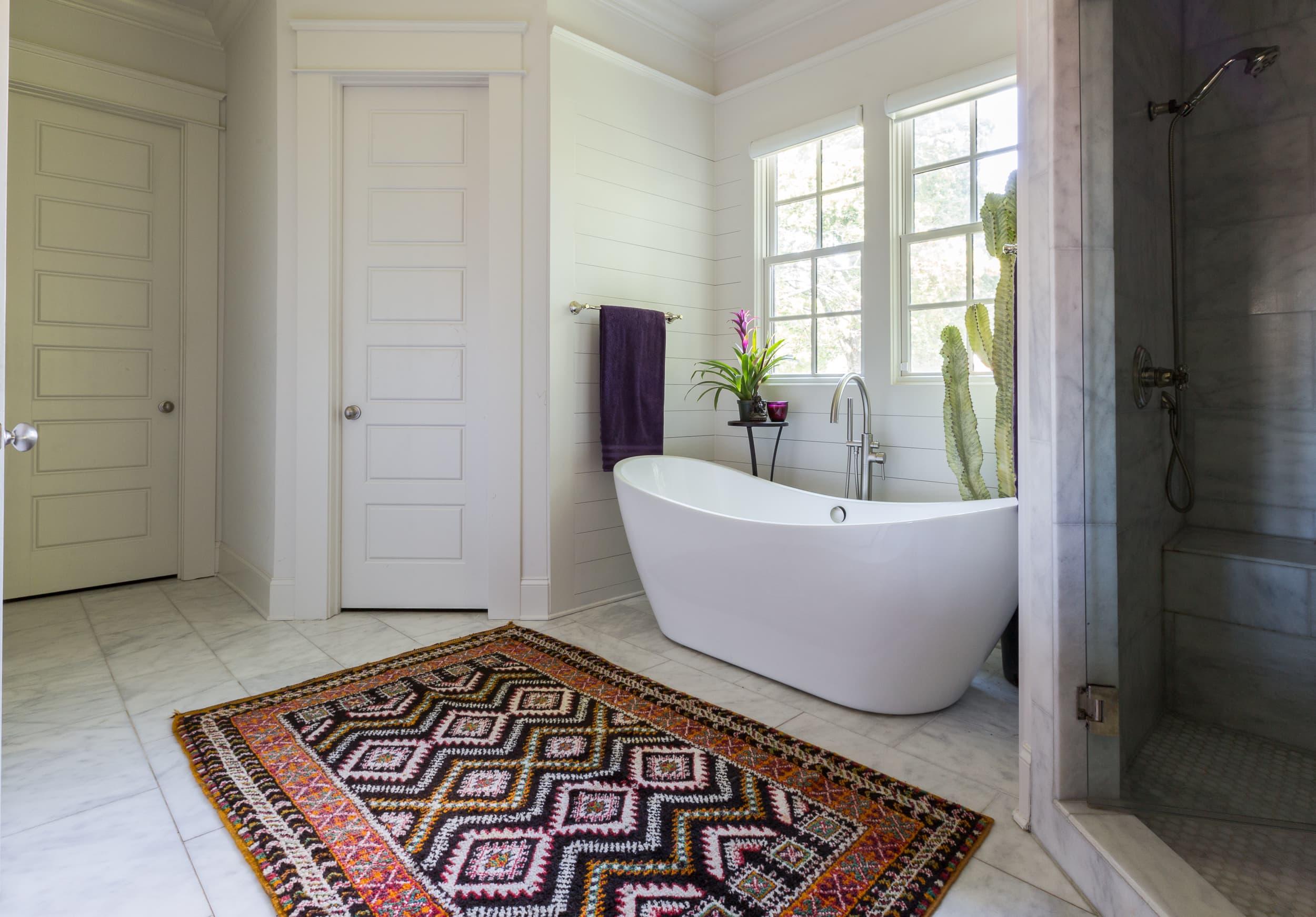 Layered rugs provide comfort and ​style in a boho bathroom